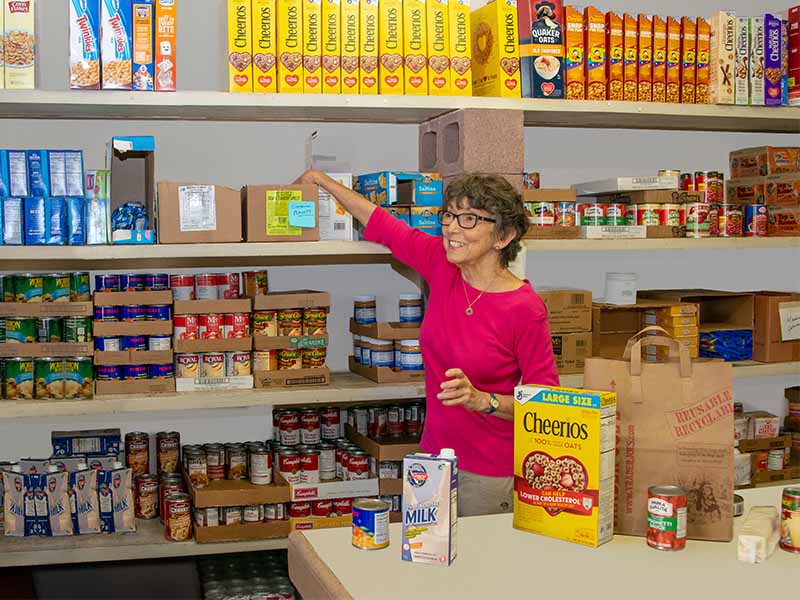 a woman smiling while stocking shelves with cans